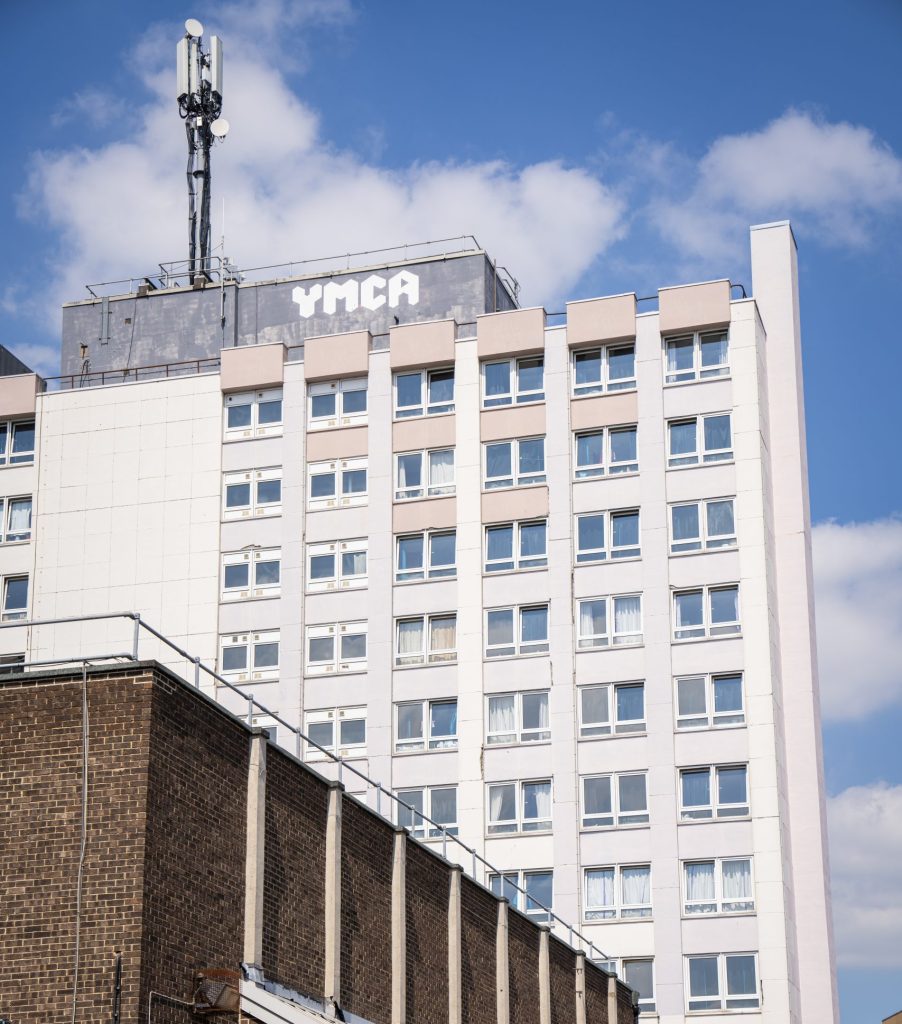 Exterior view of the YMCA Romford building against a blue sky, representing housing, community services, and support programs for local residents.